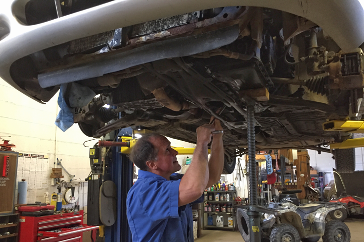 Ken Gardner performing automobile repair on a car at Kenny’s Garage in Erie PA.